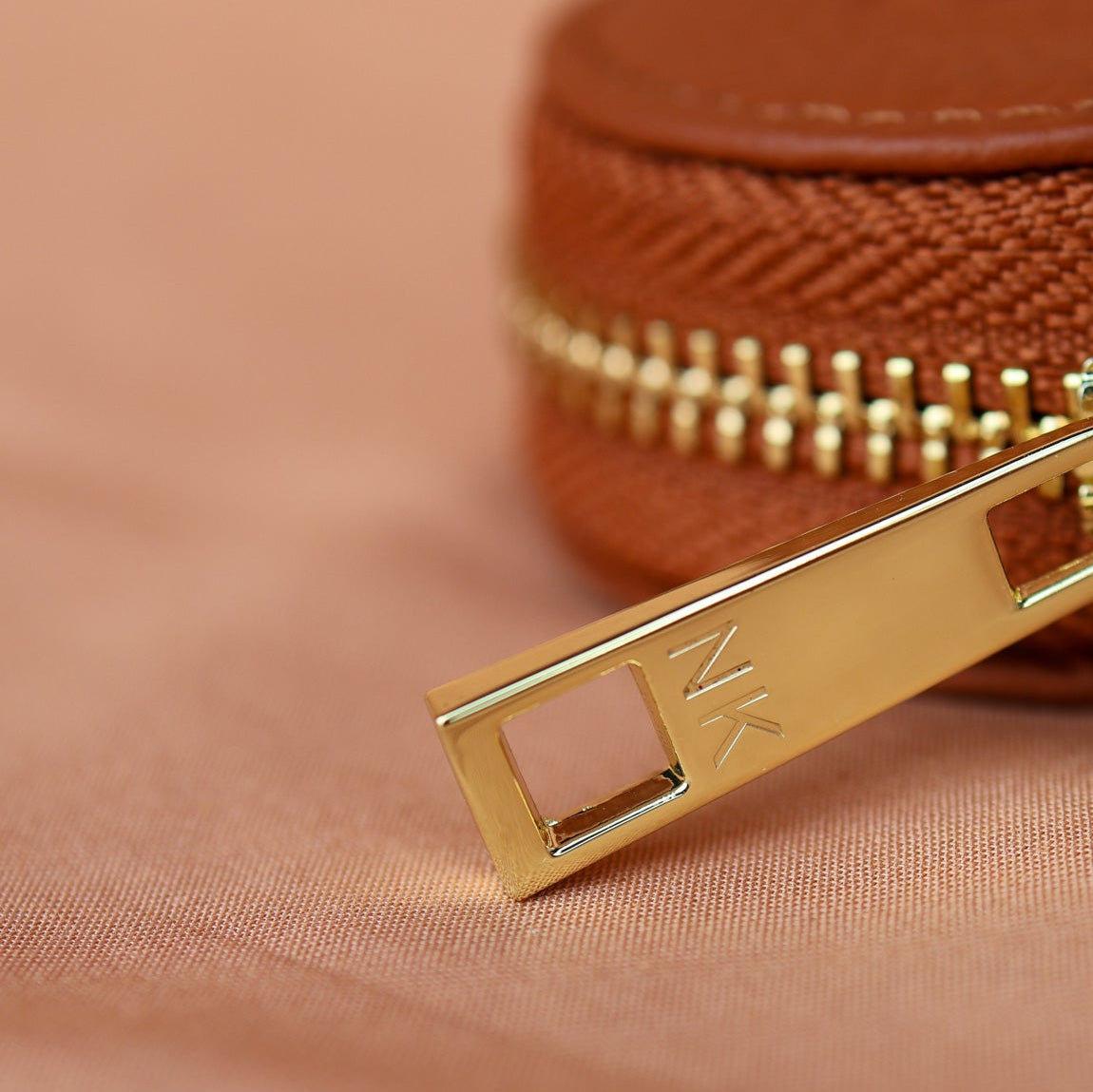 Close-up of a gold zipper on a brown fabric background