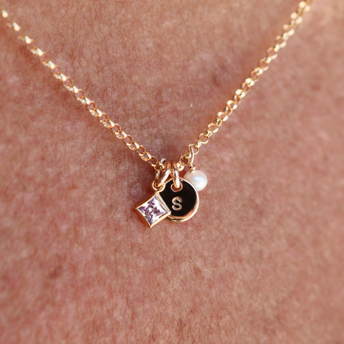 Gold necklace with a small pendant on a person's skin - KBN Jewellery - birthstone necklace - initial tiny pendant necklace