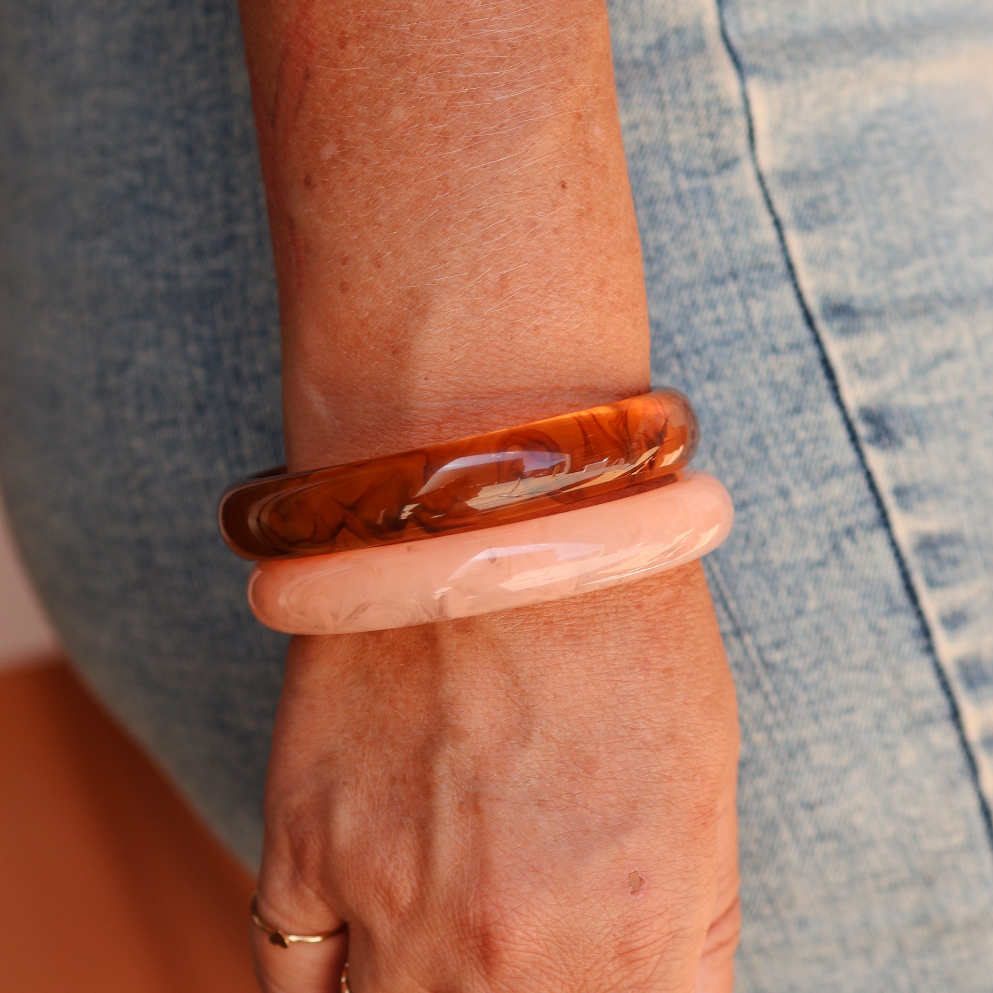 Person wearing two bangles on a wrist with a denim background - KBN RESIN BANGLES