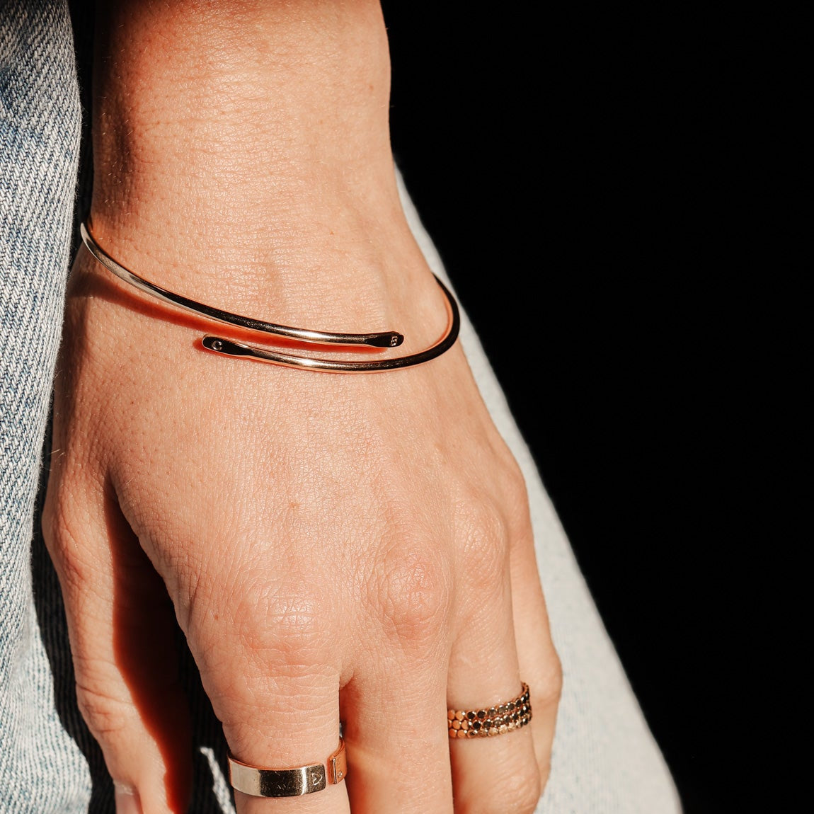 Hand wearing multiple rings with a blurred background