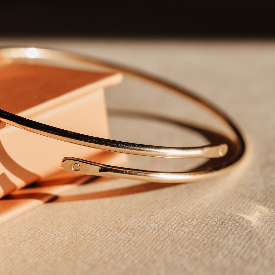 Rose gold bracelet on a beige fabric background
