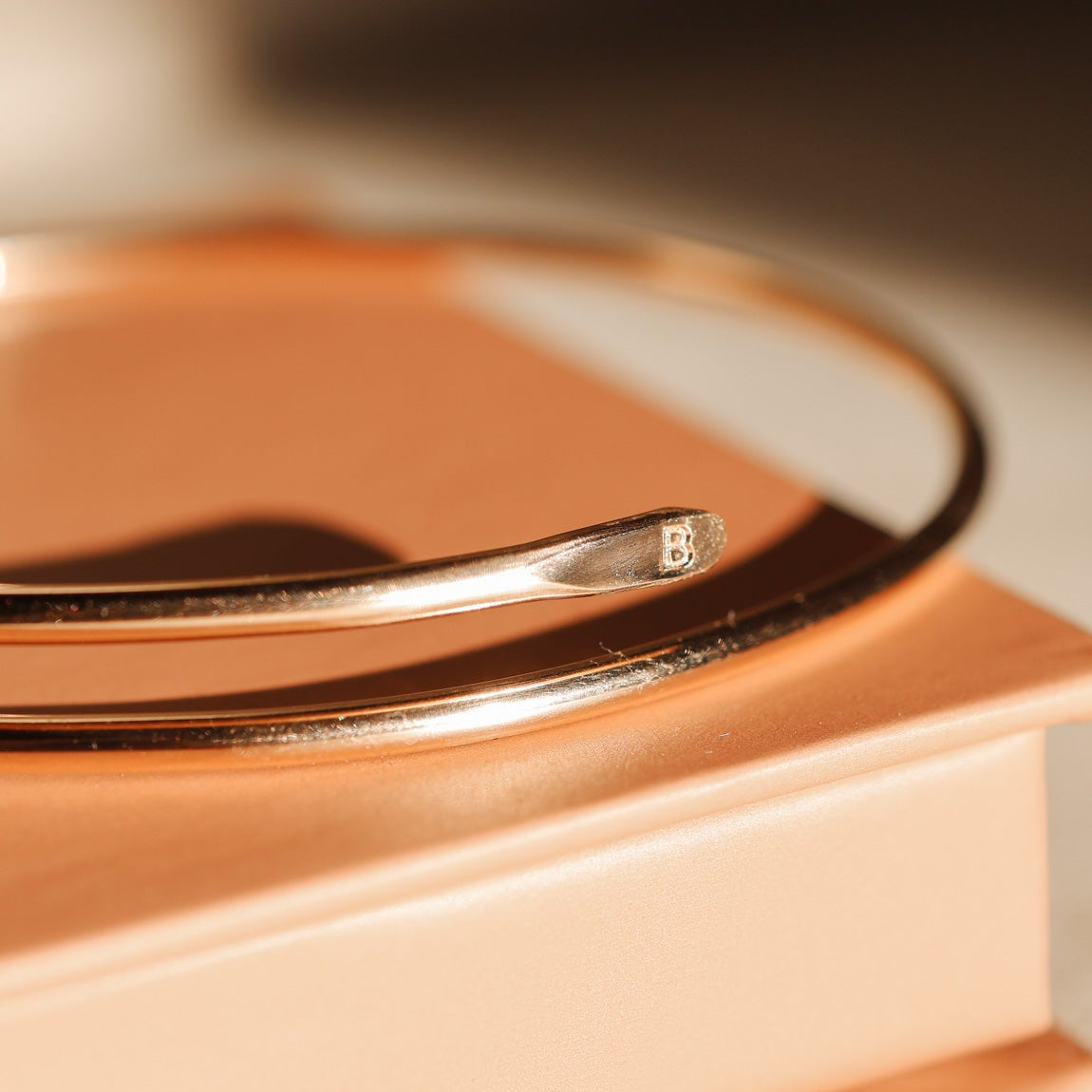 Close-up of a gold ring on a beige surface with a blurred background