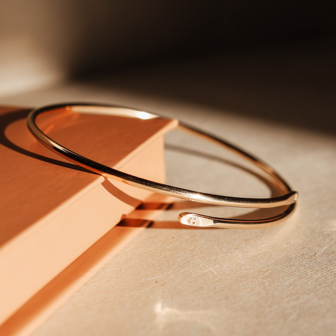 Gold bracelet on a light wooden surface with a warm glow