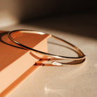 Gold bracelet on a light wooden surface with a warm glow