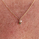Gold necklace with a small pendant on a person's neck against a pinkish-brown background - Birthstone Necklace - ting pearl necklace
