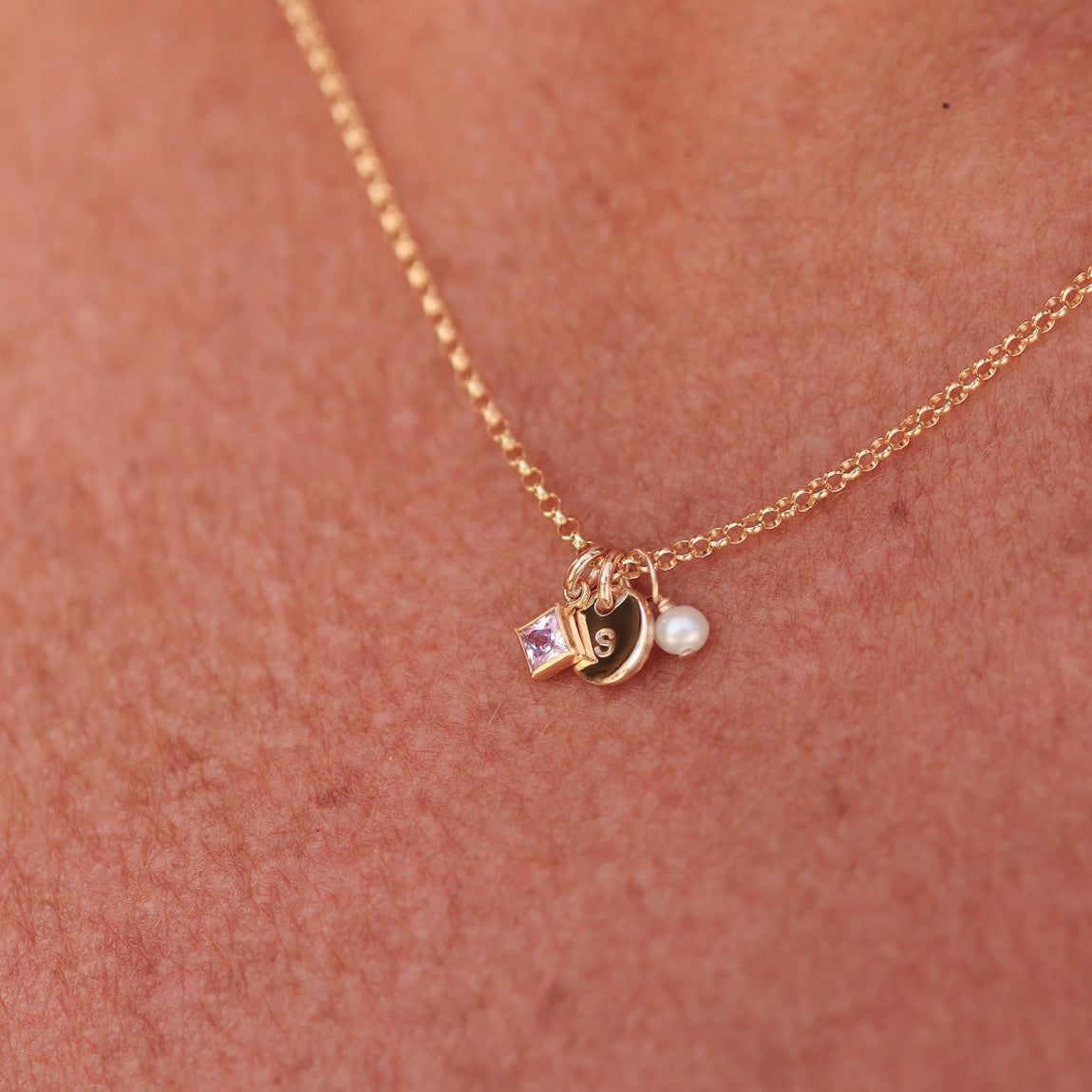 Gold necklace with birthstone, initial and pearl charm on a person's neck - KBN Jewellery -  birthstone necklace - initial tiny pendant necklace