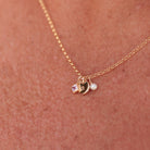 Gold necklace with birthstone, initial and pearl charm on a person's neck - KBN Jewellery -  birthstone necklace - initial tiny pendant necklace