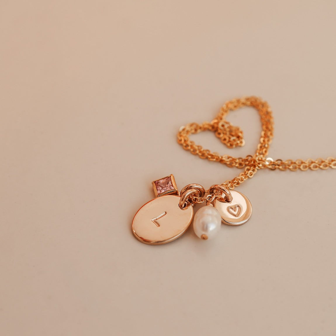 Necklace with heart-shaped clasp and charms on a beige background - birthstone cluster necklace- personalised initial necklace - kbn jewellery