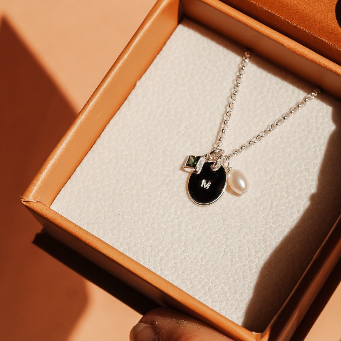 Necklace with a initial pendant and pearl held in an open brown box.  - KBN Jewellery Cluster Necklace - birthstone, initial & pearl necklace