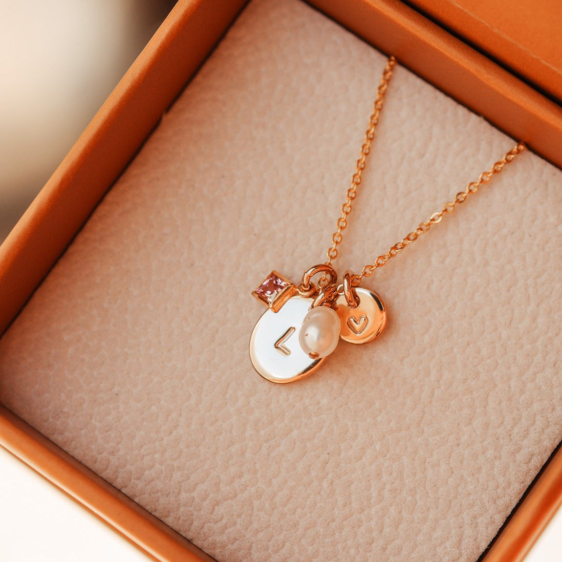 gold necklace with charms in an open jewelry box - KBN Jewellery Cluster Necklace - birthstone, initial & pearl necklace