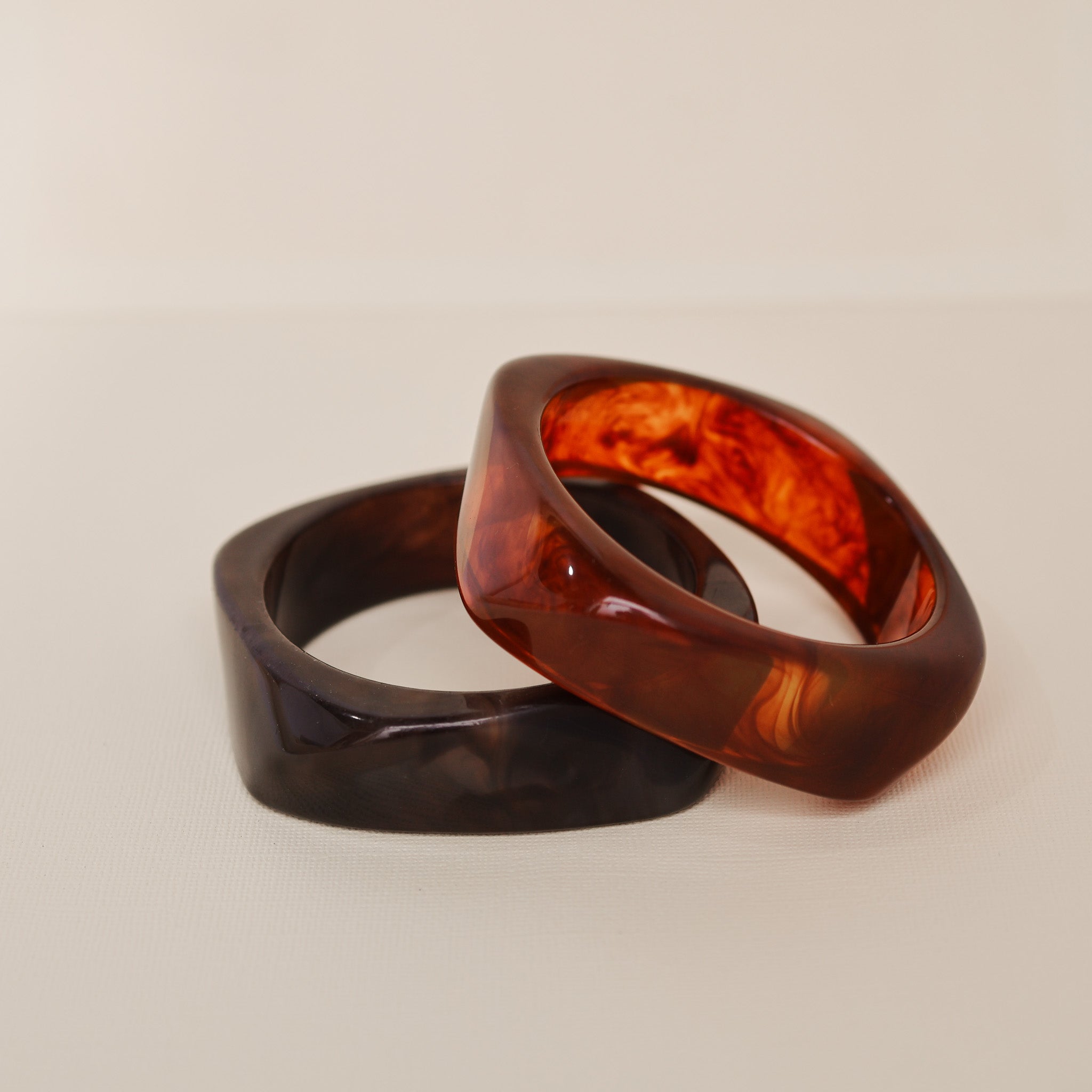 Two tortoiseshell rings on a beige background - KBN RESIN BANGLES