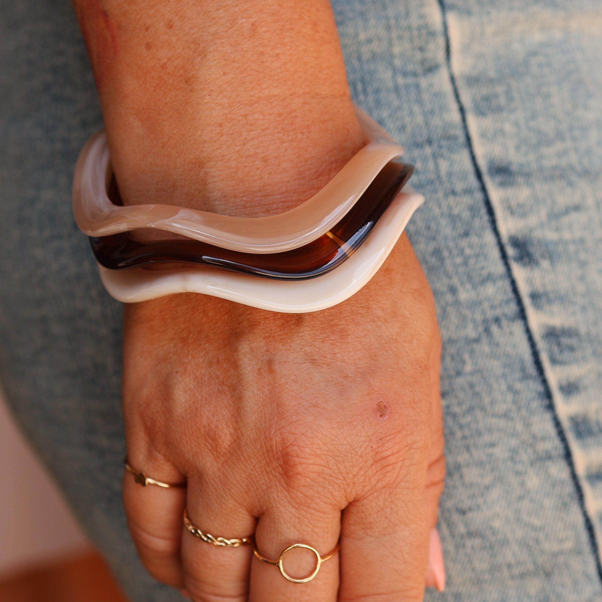 Close-up of a wrist wearing a large, curved bracelet with a neutral color palette. - KBN RESIN BANGLES